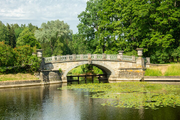 Fototapeta na wymiar The view of the 19th century stone Visconti bridge over the Slavyanka River in summertime in Pavlovsky Park, Saint Petersburg, Russia