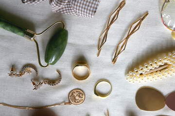 Various gold jewelry, personal accessories and beauty products on neutral background. Flat lay.