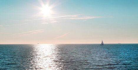 View of the sea, the ocean with a sailboat on the horizon and the bright sun and a sunny path on a...