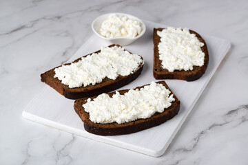 Rye bread with cottage cheese on a white table