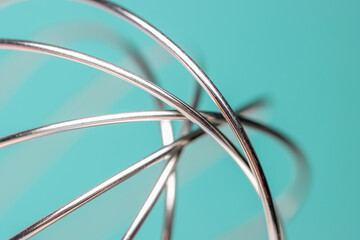 Extreme close up shot of Egg beater wires on cyan background, selective focus