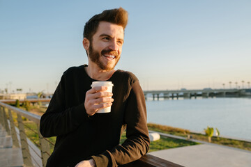 Young handsome man, smiling young man holding coffee cup, happy young man enjoying life