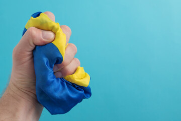 The man squeezes the Ukrainian flag in his fist. The concept of resistance and the fight against...