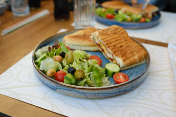 Mixed salad, egg steak toast with mixed salad on the side, olive tomatoes lettuce and cucumber, a round plate and beautiful presentation, selective focus on salad