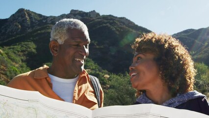 Senior couple looking at map as they hike along trail in countryside together - shot in slow motion  - Powered by Adobe