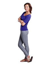 Standing with style. Full length side view of an attractive woman standing with her arms folded and smiling widely.