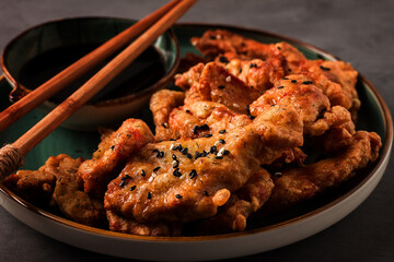 Fried meat in batter, deep-fried, with sesame seeds, and soy sauce, on a gray table, there are no people,