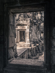Fototapeta na wymiar View from window to brightly lit ruins of ancient temple with stone carvings, Siem Reap, Cambodia