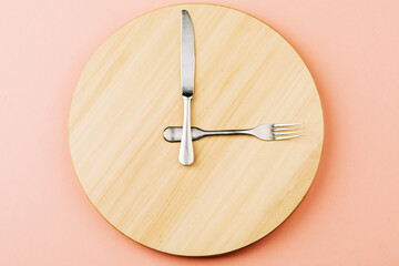 The concept of intermittent fasting and skipping meals. Wooden round tray with cutlery in the form...