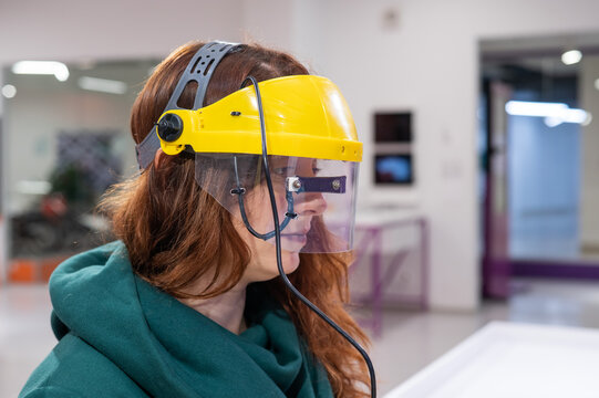 A woman in a helmet synchronizing her gaze and the movement of a computer mouse. 