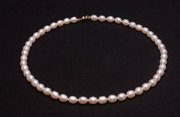 Pearl necklace on matte black background.