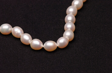 Pearl necklace on matte black background.