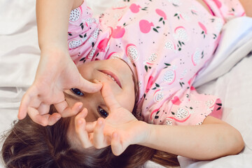 Adorable dark hair girl sleeping sweetly in the morning on wihte bed linens at home. Childrens...