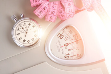 Floor scales, stopwatch and measuring tape on a white background in the bright rays of the...