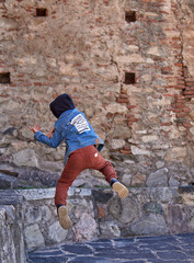 child boy in hood practicing pirouettes on old city alone. concept of a kids parkour life. vertical