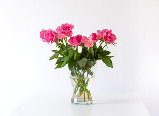 Bouquet of pink rose flowers in transparent vase.
