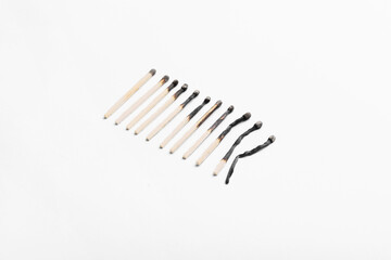 Row of differently burnt matches on white background. Concept of different human life phases