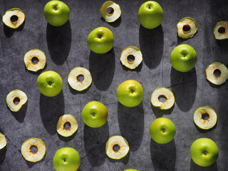 Fresh green and dried apples pattern, flat lay on dark background, top view, hard light
