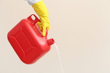 Man pouring out liquid from plastic canister on light background