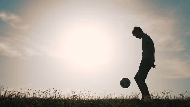 Boy with soccer ball. Child in park plays at sunset.Boy juggles soccer ball.Child dream of football match.Sports training in park. Sportsman is in control of ball. Child juggles ball.Healthy lifestyle