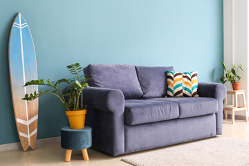Interior of stylish living room with blue sofa, houseplants and surfboard
