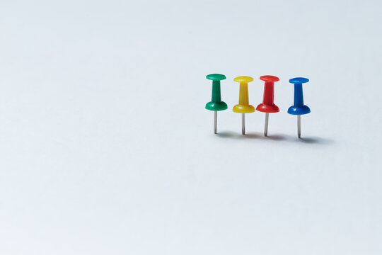 Four thumbtacks of different colour standing beside each other. Stationary supplies or concept for team work and colour personality