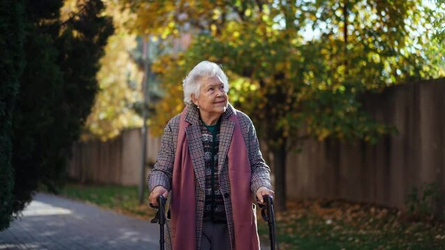 Happy senior woman on walk with walker in city in winter.