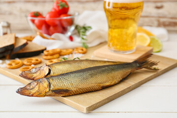 Wooden board with smoked herring fishes on table