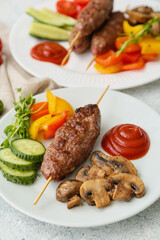 Plates of skewers with tasty lula kebab and vegetables on table