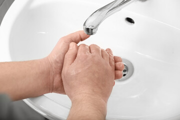 Man washing his hands with liquid soap near sink in bathroom, closeup