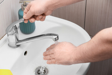 Man turning off tap in bathroom, closeup