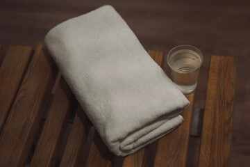 wooden bench in the gym with a white clean towel and a plastic cup of water