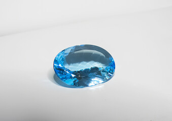 blue topaz faceted gemstone, oval shape, on white background