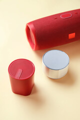 Different wireless portable speakers on color background, closeup