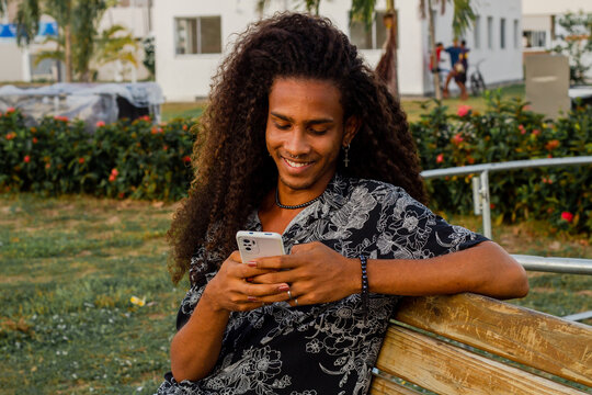 man with long curly hair checking his phone