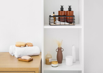 Shelf unit and table with different bath supplies near white wall