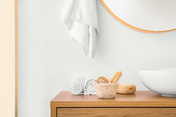 Basket with massage body brushes and bath supplies on table near sink