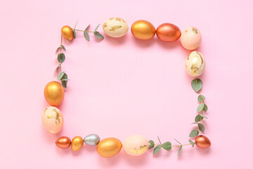 Frame made of Easter eggs and eucalyptus branches on pink background