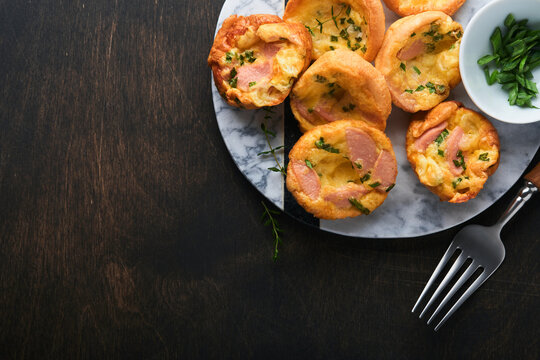 Delicious egg muffins with green onions, bacon, cheese and tomatoes on wooden board on old wooden rustic background. Healthy high protein and low carb breakfast. Homemade food.