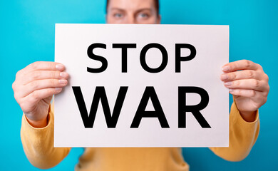 30s woman hands holding banner with inscription stop war, protesting on a blue background