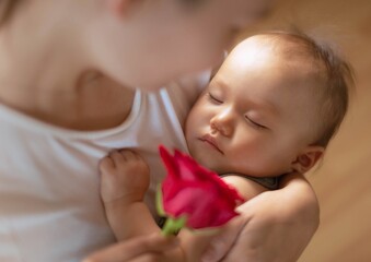 Mother's day. A mom holding her baby with a red rose gift.