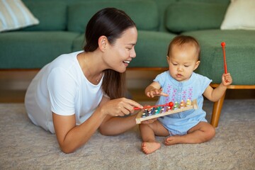 A mother playing toys and teaching her baby at home. Children learning and development.