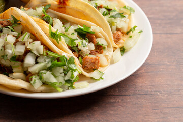 Three Chicken Street Tacos in a Row on a Wooden Table