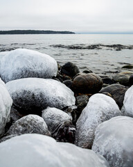 Beautiful icy stones on the winter beach. Wintery rocky beach seascape.