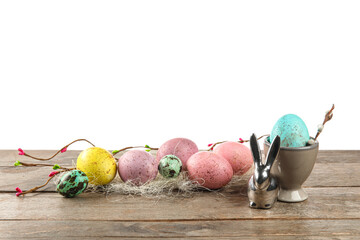 Painted Easter eggs and figurine of bunny on table against white background