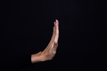 Hand of Caucasian person showing stop sign on black background. Domestic physical and psychological...