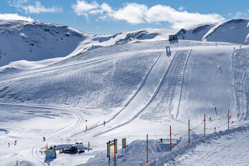 Scenic view of ski slopes and fun park in Livigno, Italy. Popular ski resort in European Alps. Snowcapped mountains, houses and ski slopes