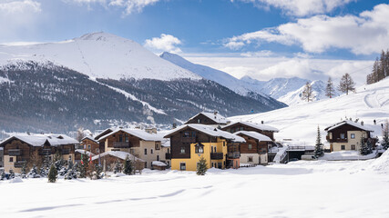 Fototapeta premium Scenic view of Livigno village in Sondrio province, Italy. Popular skiing resort in European Alps. Snowcapped mountains, houses and ski slopes