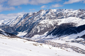 Fototapeta na wymiar Scenic view of Livigno village in Sondrio province, Italy. Popular skiing resort in European Alps. Snowcapped mountains, houses and ski slopes