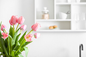 Beautiful bouquet of tulips in light kitchen, closeup